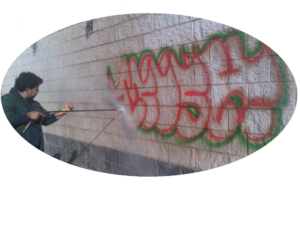 A man spraying graffiti on the side of a building.